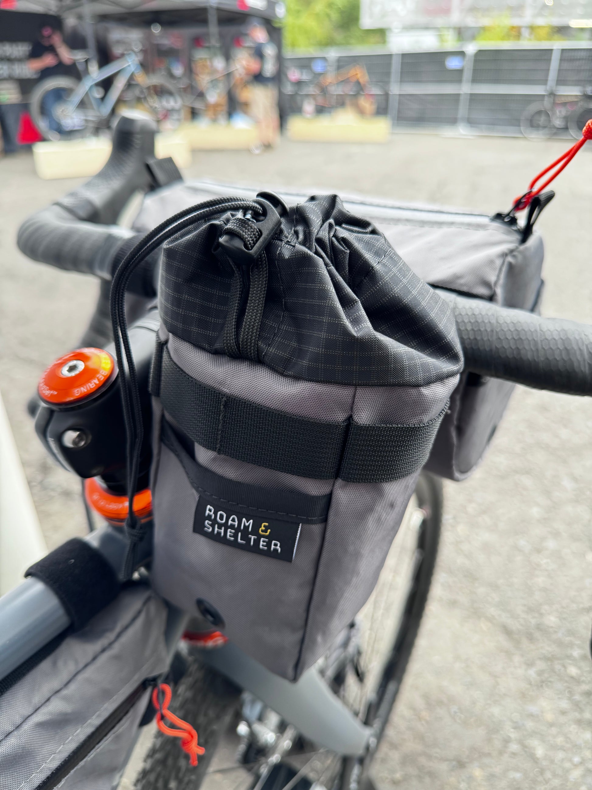 A gray stem bag attached to a bicycle's stem and handlebar, featuring a drawstring closure and made of Ecopak 400 material.  Two external pockets.  Handmade in Portland Oregon USA.